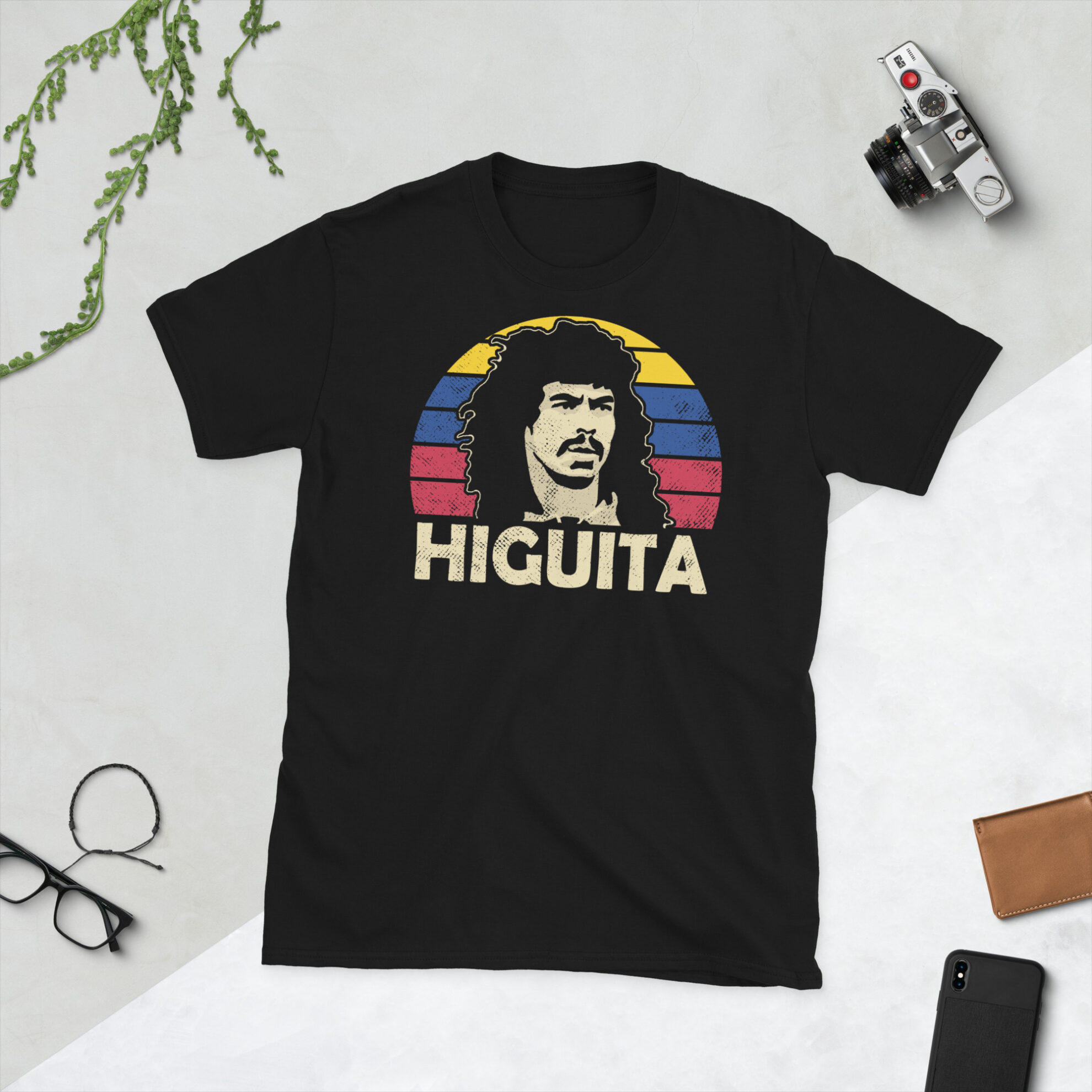 René Higuita Colombia T-Shirt in Black - A black T-shirt featuring a Colombia sunburst graphic and the word "HIGUITA" in the colours of the Columbian flag, honoring Colombian football legend René Higuita.