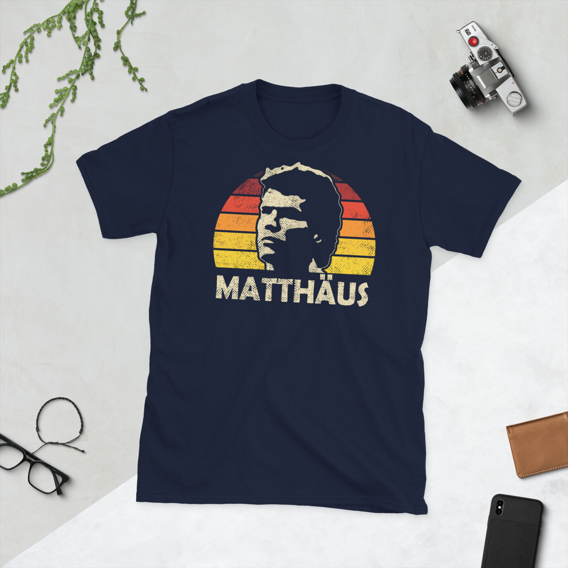 Lothar Matthäus T-Shirt in Navy: A navy T-shirt featuring a black, red, and gold sunburst and the word "MATTHÄUS" in bold, paying tribute to German football legend Lothar Matthäus.