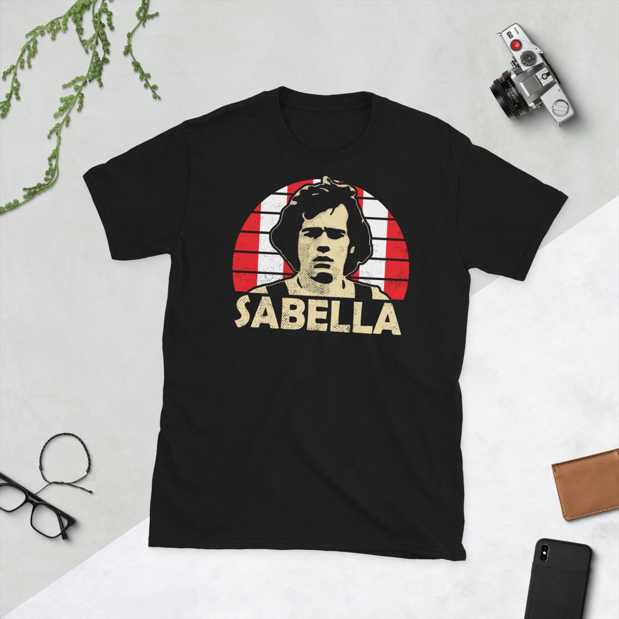 Alejandro Sabella T-Shirt in Black: A black T-shirt featuring an Estudiantes de La Plata sunburst and the word "SABELLA" in bold, honoring Argentine football legend Alejandro Sabella.