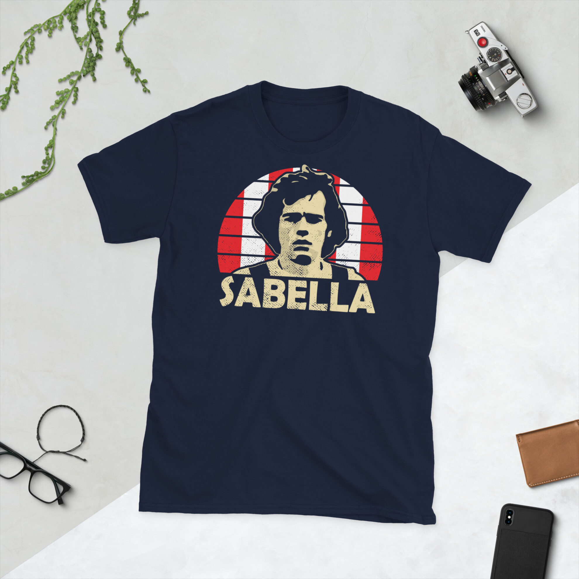 Alejandro Sabella T-Shirt in Navy: A navy T-shirt featuring an Estudiantes de La Plata sunburst and the word "SABELLA" in bold, paying tribute to Argentine football legend Alejandro Sabella.