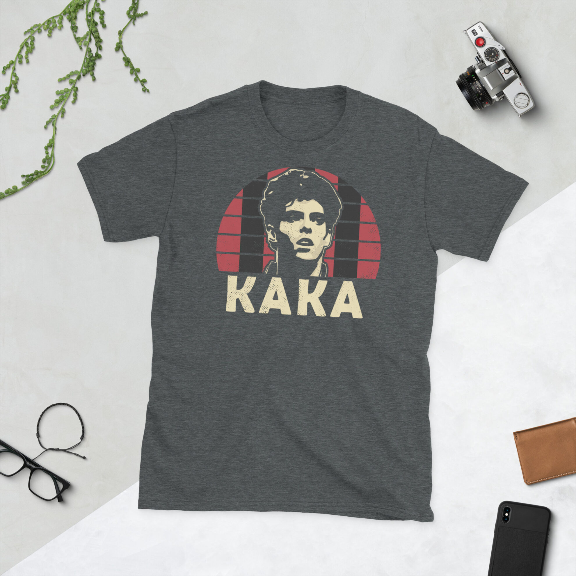 A heather grey Kaka T-Shirt featuring a red and black striped sunburst design (inspired by AC Milan colours) and "KAKA" printed prominently in bold.