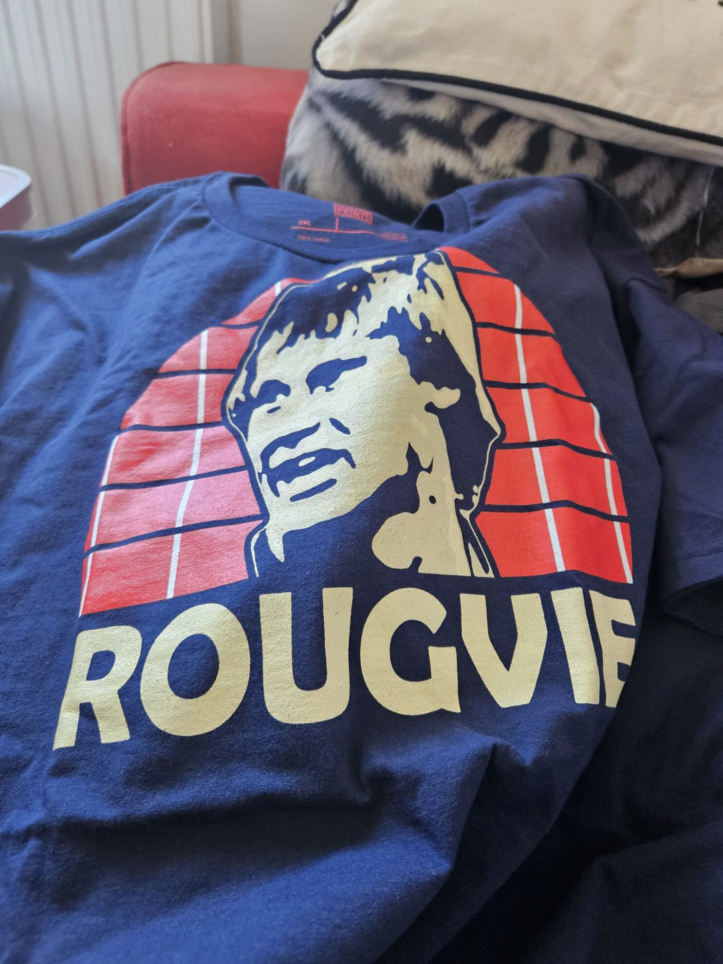 A navy t-shirt featuring Aberdeen FC legend Doug Rougvie. T-shirt is lying over the customers sofa.