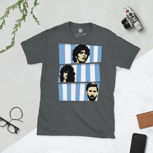 A dark heather T-shirt featuring three stacked bands of blue and white stripes, each containing a stencil image of an Argentina World Cup winner: Diego Maradona, Mario Kempes, and Lionel Messi.