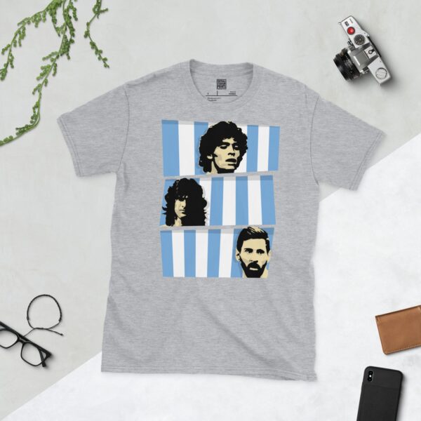 A sports grey T-shirt featuring three stacked bands of blue and white stripes, each containing a stencil image of an Argentina World Cup winner: Diego Maradona, Mario Kempes, and Lionel Messi.