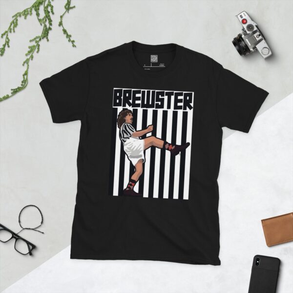 A black t-shirt featuring an illustration of fictional footballer Tubby Brewster in a striped kit, mid-kick, against a black and white striped background, with "BREWSTER" in bold white text above.