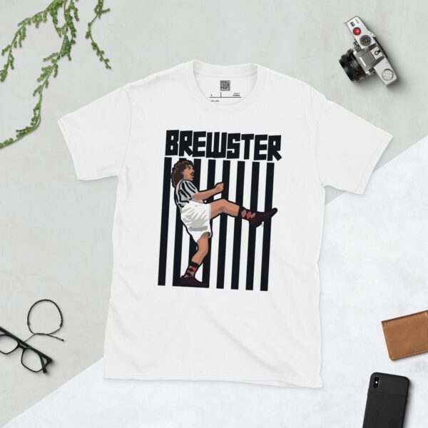 A white t-shirt featuring an illustration of fictional footballer Tubby Brewster in a striped kit, mid-kick, against a black and white striped background, with "BREWSTER" in bold black text above.