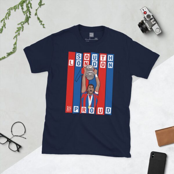 A navy blue T-shirt featuring a graphic of Crystal Palace legend Joel Ward lifting the FA Cup, set against bold blue and red stripes. The text "SOUTH LONDON" is at the top and "AND PROUD" is at the bottom.