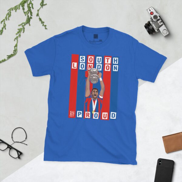 A royal blue T-shirt featuring a graphic of Crystal Palace legend Joel Ward lifting the FA Cup, set against bold blue and red stripes. The text "SOUTH LONDON" is at the top and "AND PROUD" is at the bottom.