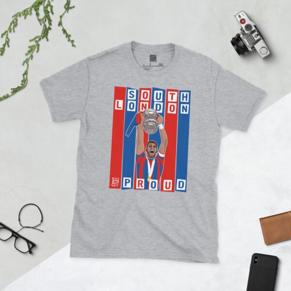 A sports grey T-shirt featuring a graphic of Crystal Palace legend Joel Ward lifting the FA Cup, set against bold blue and red stripes. The text "SOUTH LONDON" is at the top and "AND PROUD" is at the bottom.