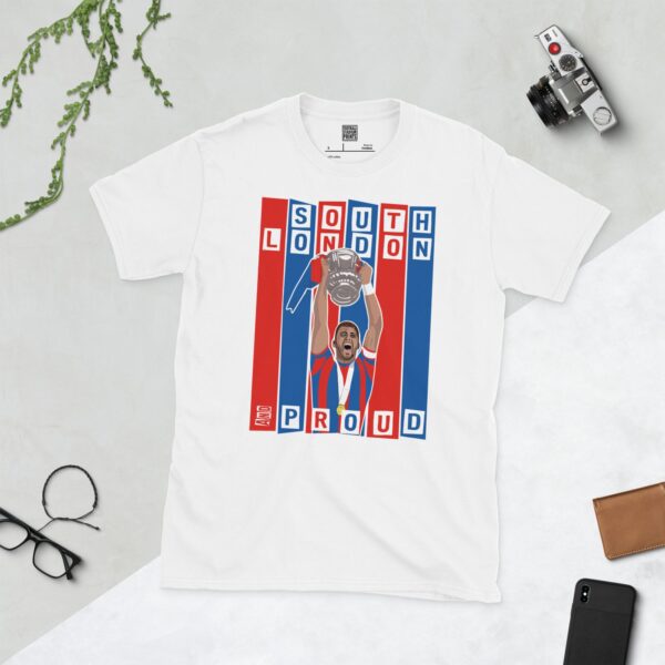 A white T-shirt featuring a graphic of Crystal Palace legend Joel Ward lifting the FA Cup, set against bold blue and red stripes. The text "SOUTH LONDON" is at the top and "AND PROUD" is at the bottom.