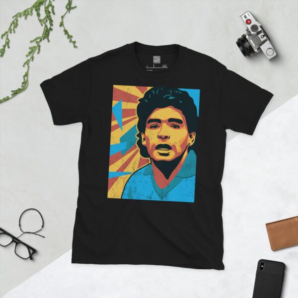 A black T-shirt featuring a colourful, distressed graphic of Diego Maradona with a blue shirt and yellow and red background elements.
