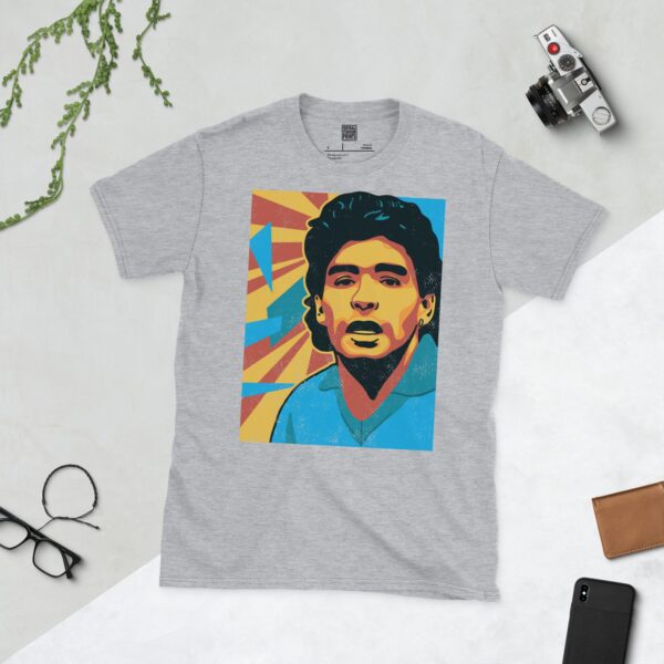 A sports grey T-shirt featuring a colourful, distressed graphic of Diego Maradona with a blue shirt and yellow and red background elements.
