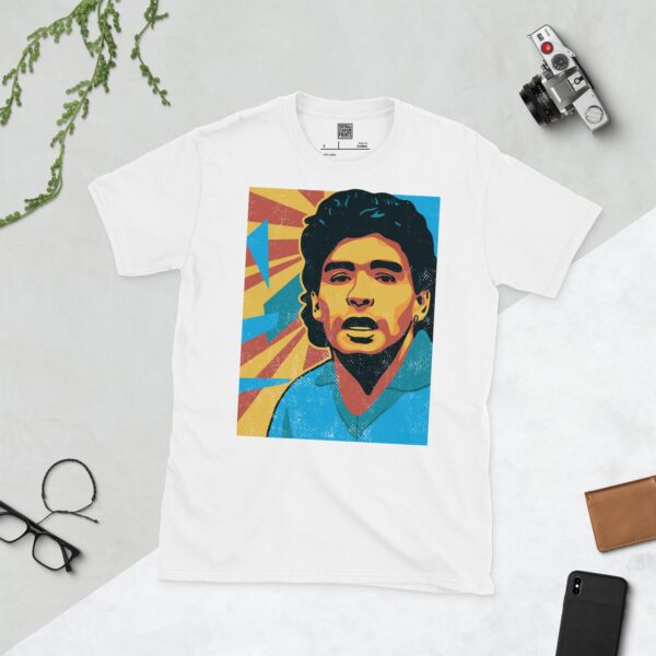 A white T-shirt featuring a colourful, distressed graphic of Diego Maradona with a blue shirt and yellow and red background elements.