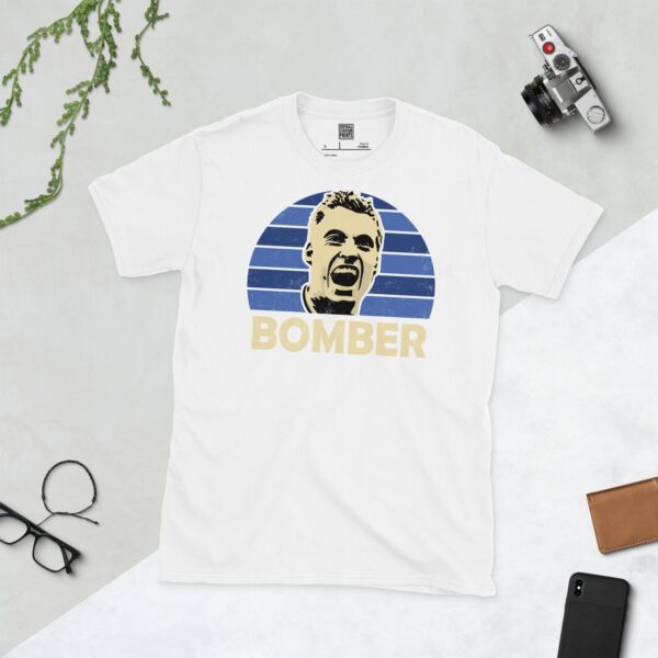 Show your Millwall pride in this white Neil "Bomber" Harris T-shirt. It features a blue sunburst design with "BOMBER" written under the main graphic.