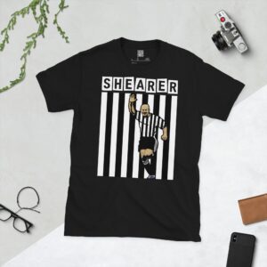 Black: A bold black T-shirt featuring an illustration of Alan Shearer in his iconic Newcastle United black and white striped kit, arm raised in celebration. His name "SHEARER" is prominently displayed in white blocks above him against a striped background.