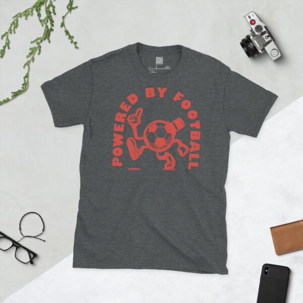 A dark heather T-shirt featuring a distressed red graphic of a cartoon football character with a top hat, arms, and legs, pointing upwards. The text "POWERED BY FOOTBALL" is arranged in a circular design around it.