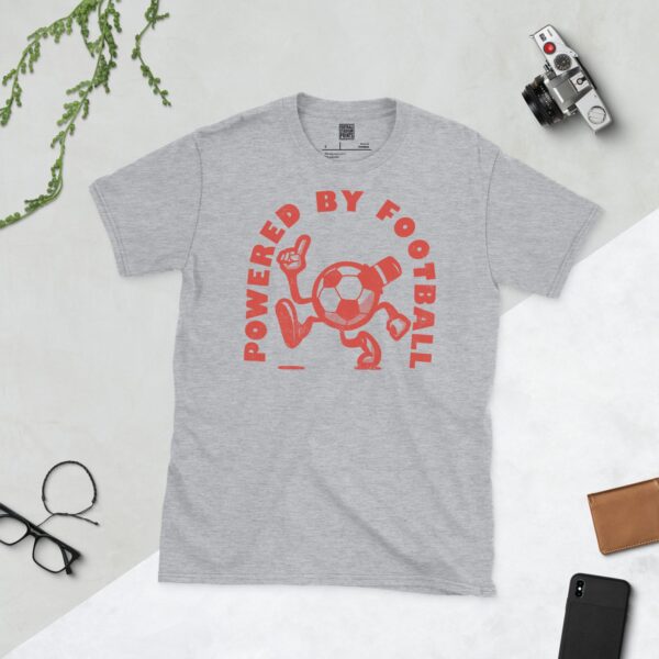 A sports grey T-shirt featuring a distressed red graphic of a cartoon football character with a top hat, arms, and legs, pointing upwards. The text "POWERED BY FOOTBALL" is arranged in a circular design around it.