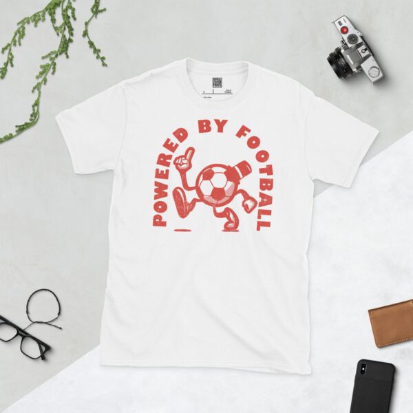 A white T-shirt featuring a distressed red graphic of a cartoon football character with a top hat, arms, and legs, pointing upwards. The text "POWERED BY FOOTBALL" is arranged in a circular design around it.