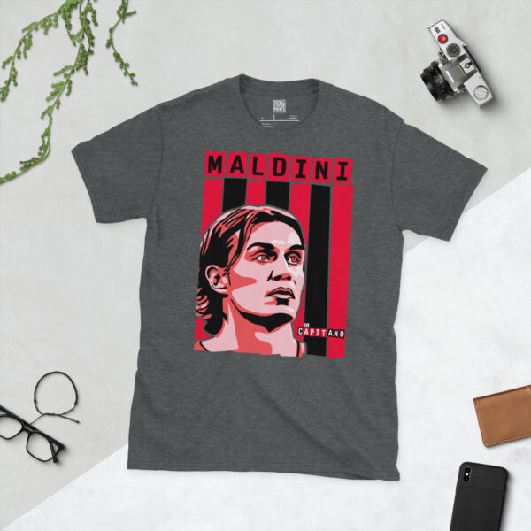A subtle dark heather T-shirt emblazoned with a striking portrait of former AC Milan defensive maestro Paolo Maldini. The design incorporates the famous red and black stripes behind his image, alongside his name "MALDINI" and the fitting title "IL CAPITANO".