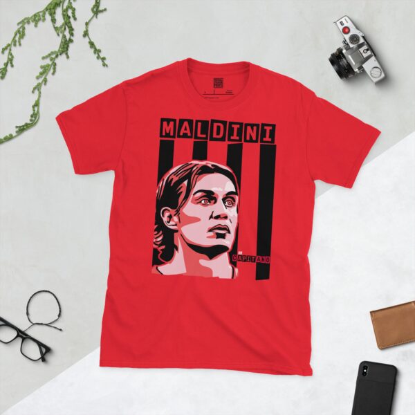 A vibrant red T-shirt showcasing a stylised graphic of AC Milan legend Paolo Maldini's face. The background features bold black vertical stripes, with his surname "MALDINI" at the top and "IL CAPITANO" integrated into the design, honouring his legacy.
