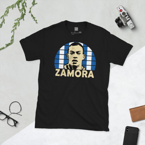 A bold black T-shirt emblazoned with a striking portrait of Brighton & Hove Albion icon Bobby Zamora. The graphic depicts his face against a backdrop of blue and white vertical stripes, and his surname "ZAMORA" is a central feature below the image.