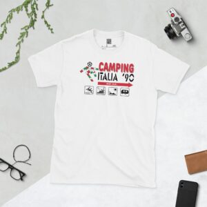 A clean white T-shirt featuring a retro graphic inspired by an Italia '90 camping sign. The design includes "CAMPING ITALIA '90", a football icon, and four small pictograms (tent, boat, sunbather, caravan) with an arrow and "50 mt.", all set against a subtle green and red background mimicking the Italian flag.