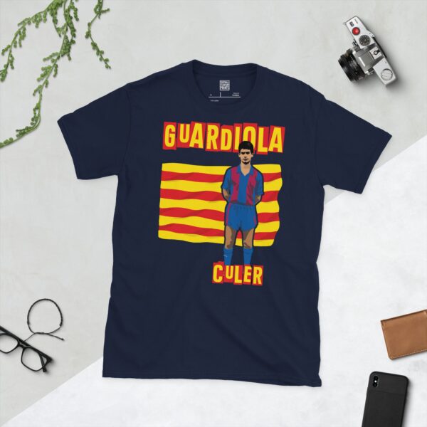 A deep navy blue T-shirt featuring a compelling graphic of a young Pep Guardiola, the legendary Barcelona player, with his image set against a vivid red and yellow striped flag. The iconic word "CULER" is clearly visible, paying tribute to his deep connection to the club.