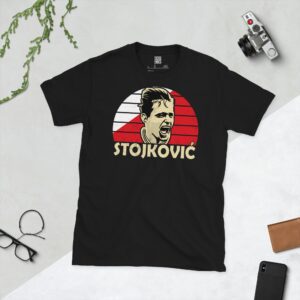 A bold black T-shirt emblazoned with a striking portrait of Red Star Belgrade icon Dragan Stojković. The graphic depicts his face against a backdrop of red and white sunburst lines, and his surname "STOJKOVIĆ" is a central feature below the image.