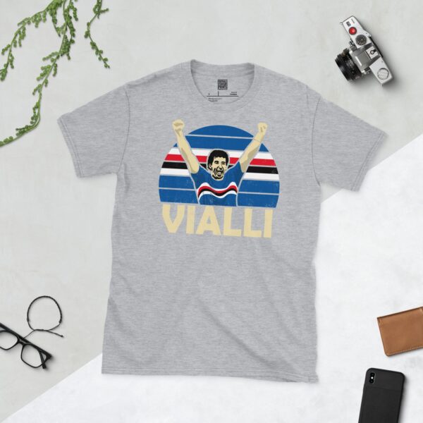 A versatile sports grey T-shirt showcasing a dynamic illustration of Gianluca Vialli, the beloved Sampdoria striker. The design includes his celebratory pose over a bold striped pattern, with "VIALLI" clearly visible underneath.