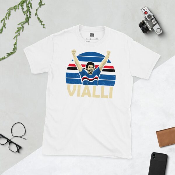 A clean white T-shirt featuring a stylised graphic of Sampdoria legend Gianluca Vialli celebrating with his arms raised, set against a circular background with the club's iconic blue, white, red, and black stripes. His surname "VIALLI" is displayed below the portrait.