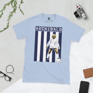 A baby blue T-shirt featuring a compelling graphic of Steve Archibald, the legendary Tottenham Hotspur forward, with his image set against bold navy and white vertical stripes. His iconic surname "ARCHIBALD" is clearly visible, paying tribute to his time at the club.