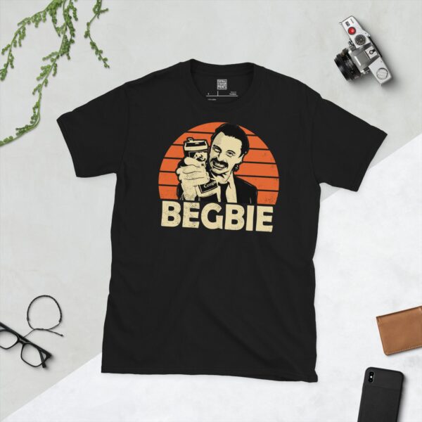 A bold black T-shirt emblazoned with a striking portrait of the Trainspotting character Francis Begbie. The graphic depicts his face against a backdrop of orange sunburst lines, and his surname "BEGBIE" is a central feature below the image.