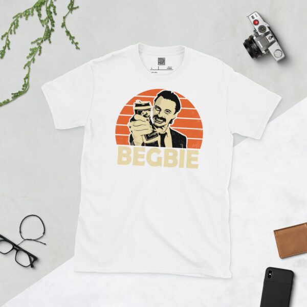 A clean white T-shirt featuring a stylized graphic of the character Francis Begbie from Trainspotting. He is shown with a drink in hand and a smirk, against a distressed orange sunburst background, with his surname "BEGBIE" prominently displayed below the portrait.
