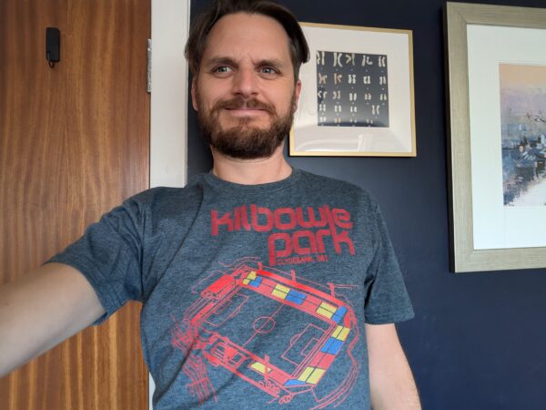 A customer wearing a dark heather Clydebank Kilbowie Park t-shirt