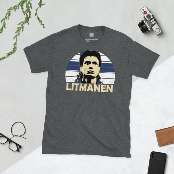 A subtle dark heather T-shirt displaying a distinctive graphic of former Finnish football maestro Jari Litmanen. His portrait is captured against a retro blue and white sunburst effect, with his surname "LITMANEN" directly beneath the illustration.