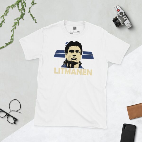 A clean white T-shirt featuring a stylised graphic of Finnish football legend Jari Litmanen's face, set against a vibrant sunburst background of the Finnish flag's blue and white colours. His surname "LITMANEN" is prominently displayed below the portrait.