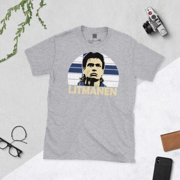 A versatile sports grey T-shirt showcasing a dynamic illustration of Jari Litmanen, the iconic Finland attacking midfielder. The design includes his portrait over a bold blue and white radiating pattern, with "LITMANEN" clearly visible underneath.