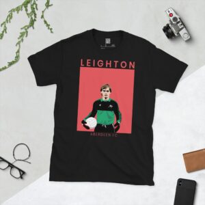 A black T-shirt featuring a stylised graphic of Aberdeen legend Jim Leighton in a goalkeeper kit. The surname "LEIGHTON" is printed above the image and "ABERDEEN FC" is printed below it, all set against a faded red background.