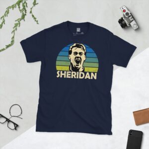 A deep navy blue T-shirt featuring a compelling graphic of John Sheridan, the legendary Leeds United player, with his image set against a vivid sunburst design that fades from blue to yellow. His iconic surname "SHERIDAN" is clearly visible, paying tribute to his time at the club.