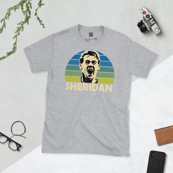 A versatile sports grey T-shirt showcasing a dynamic illustration of John Sheridan, the beloved Leeds United midfielder. The design includes his portrait over a bold sunburst that fades from blue to yellow, with "SHERIDAN" clearly visible underneath.