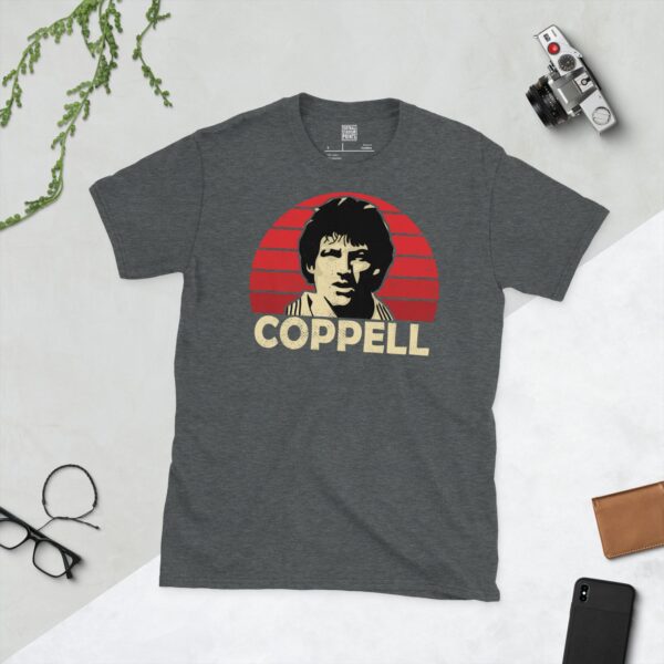 A subtle dark heather T-shirt displaying a distinctive graphic of former Manchester United winger Steve Coppell. His portrait is captured against a retro red sunburst effect, with his surname "COPPELL" directly beneath the illustration.