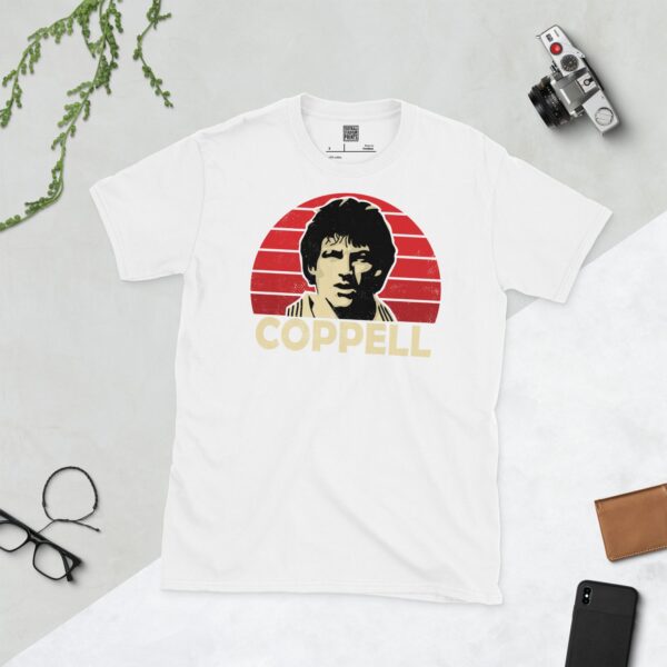 A clean white T-shirt featuring a stylised graphic of Manchester United legend Steve Coppell, set against a vibrant red sunburst background. His surname "COPPELL" is prominently displayed below the portrait.