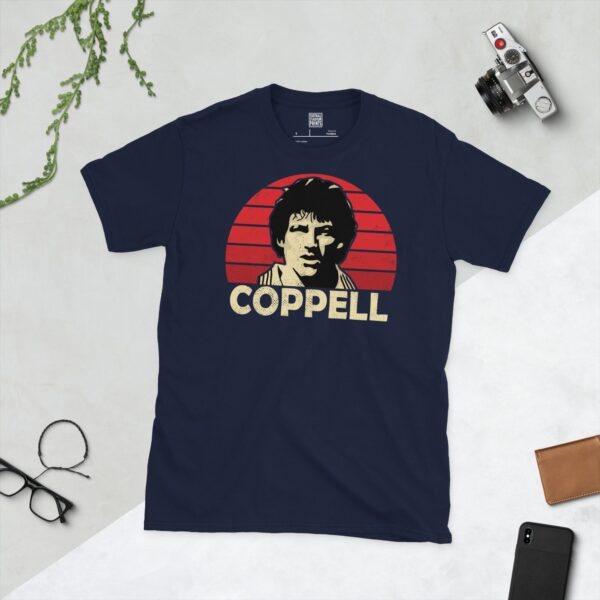 A deep navy blue T-shirt featuring a compelling graphic of Steve Coppell, the legendary Manchester United player, with his image set against a vivid red sunburst design. His iconic surname "COPPELL" is clearly visible, paying tribute to his time at the club.