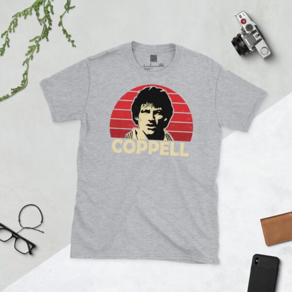 A versatile sports grey T-shirt showcasing a dynamic illustration of Steve Coppell, the beloved Manchester United winger. The design includes his portrait over a bold red radiating pattern, with "COPPELL" clearly visible underneath.
