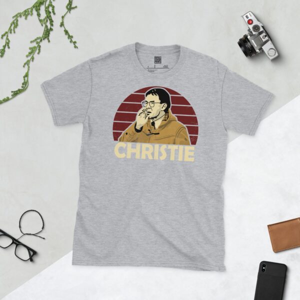 A versatile sports grey T-shirt showcasing a dynamic illustration of Terry Christie, the beloved Stenhousemuir manager. The design includes his portrait over a bold burgundy radiating pattern, with "CHRISTIE" clearly visible underneath.
