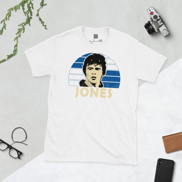 A clean white T-shirt featuring a stylised graphic of Bristol Rovers legend Vaughan Jones's face, set against a vibrant sunburst background of blue and white squares. His surname "JONES" is prominently displayed below the portrait.