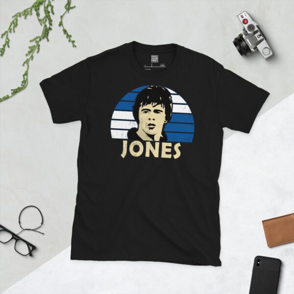 A bold black T-shirt emblazoned with a striking portrait of Bristol Rovers' Vaughan Jones. The graphic depicts his face against a backdrop of blue and white squares, and his surname "JONES" is a central feature below the image.