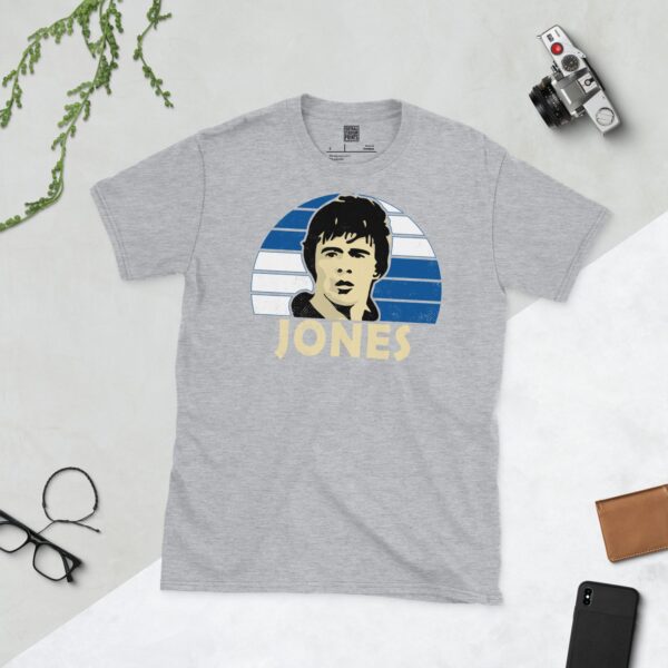 A versatile sports grey T-shirt showcasing a dynamic illustration of Vaughan Jones, the memorable Bristol Rovers defender. The design includes his portrait over a bold blue and white quartered radiating pattern, with "JONES" clearly visible underneath.