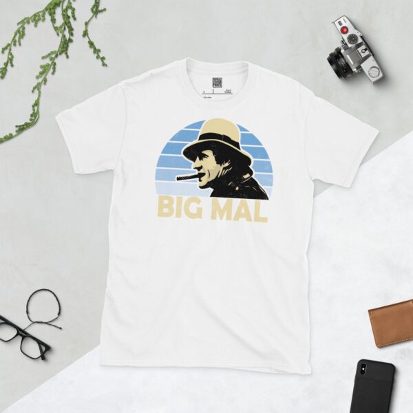A white T-shirt with a bold portrait of football manager Malcolm Allison. The image is set against a light blue faded sunburst background with the nickname "BIG MAL" in light yellow underneath.