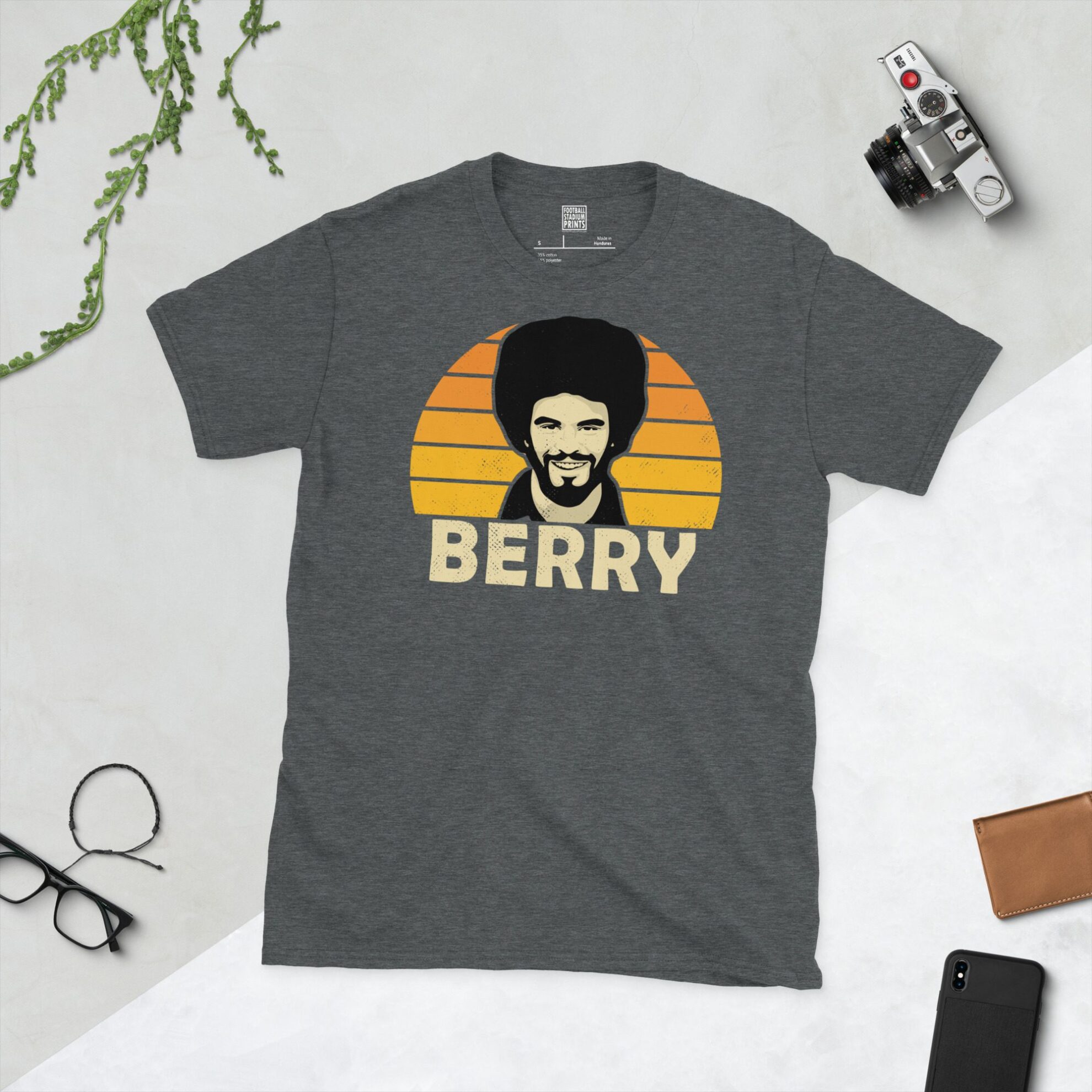 A dark heather T-shirt showing a clean, modern portrait of George Berry, the Molineux icon, with "BERRY" printed in light yellow below the image on a Golden Orange sunburst background.